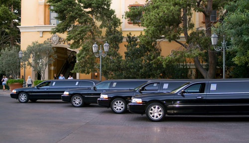 Four black limos are parked outside a building.