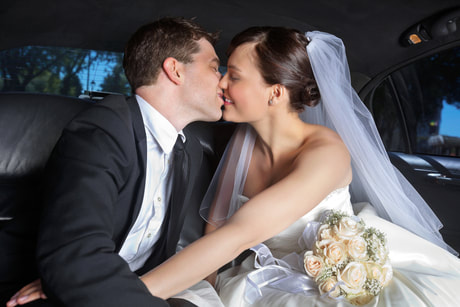 Newlyweds kissing inside their limo.