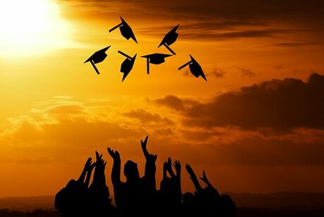 Visual image of graduates throwing their caps in the air.