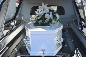 A white small casket in a hearse.